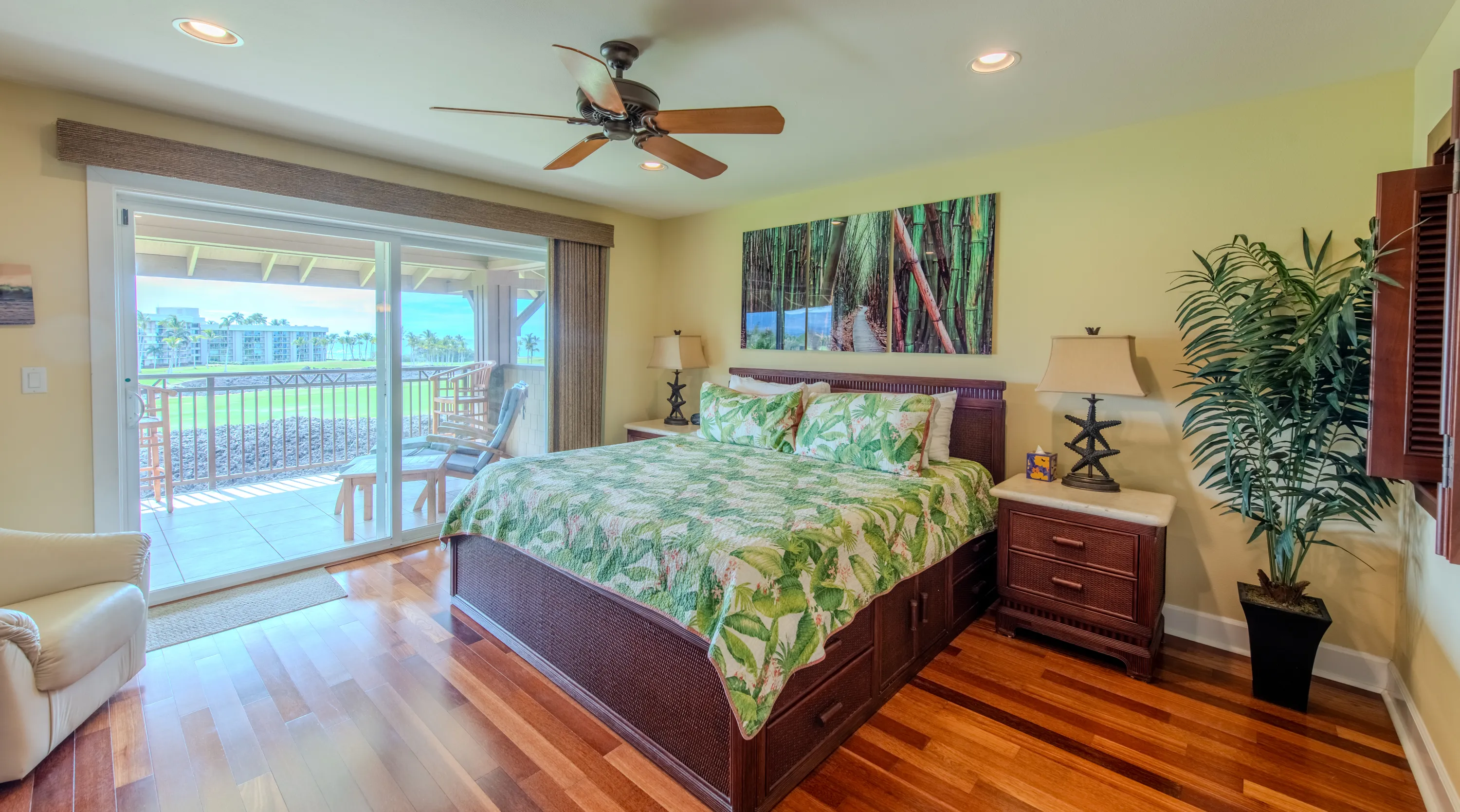 Bedroom with island-print bedding opening to a lanai over the golf course